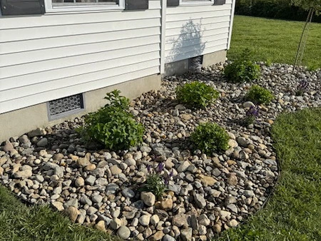 Decorative stone landscape bed installed around a coastal Delaware home